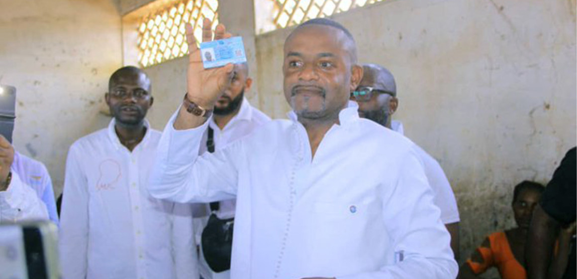 Salomon Idi Kalonda exhibe sa carte d'électeur après son enrôlement