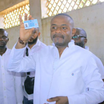 Salomon Idi Kalonda exhibe sa carte d'électeur après son enrôlement